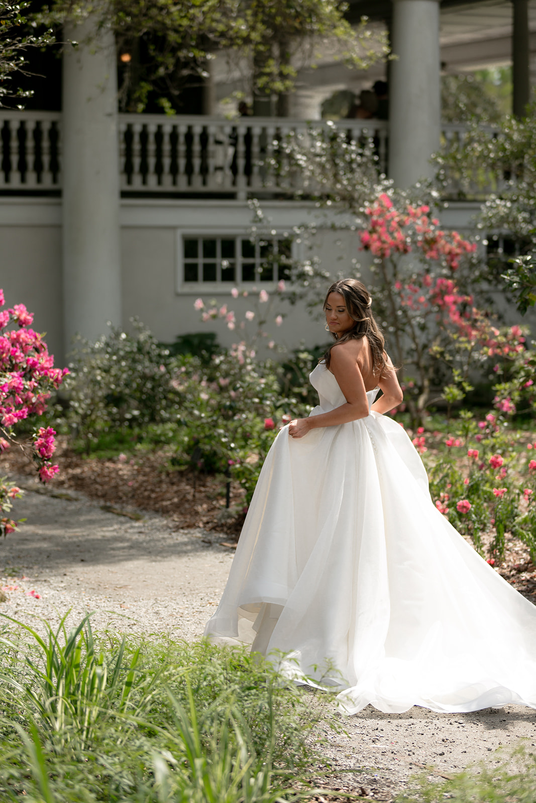 Bride walking down path at Magnolia Plantation surrounded by flowers.