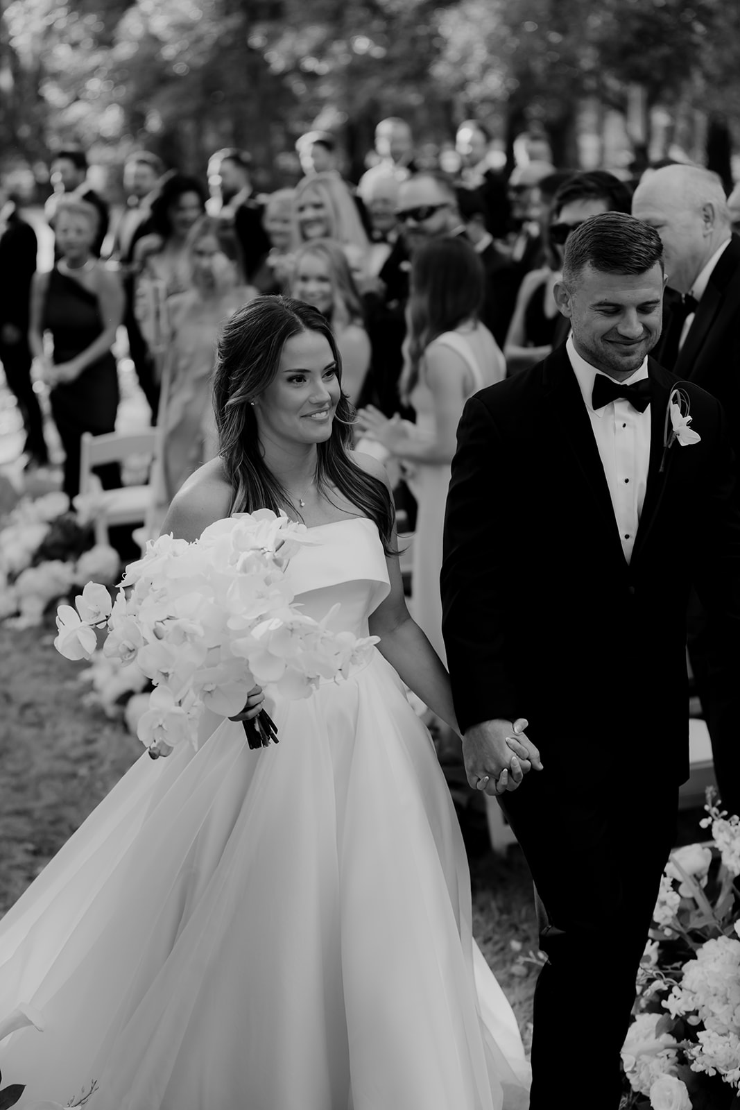 Black and white photo of bride and groom walking down the aisle as newlyweds