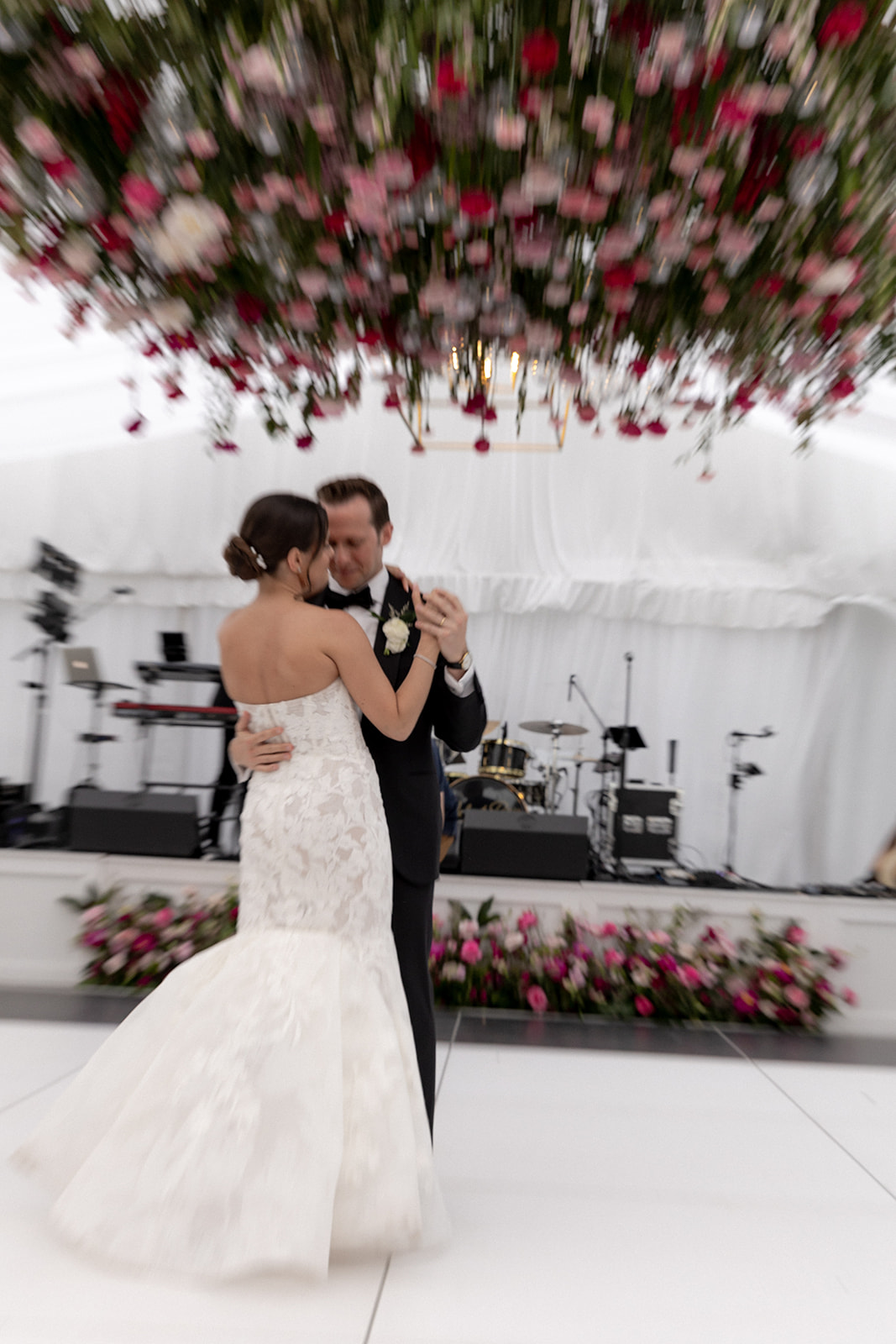 Artsy photo of bride and groom dancing under hangig flower arrangement