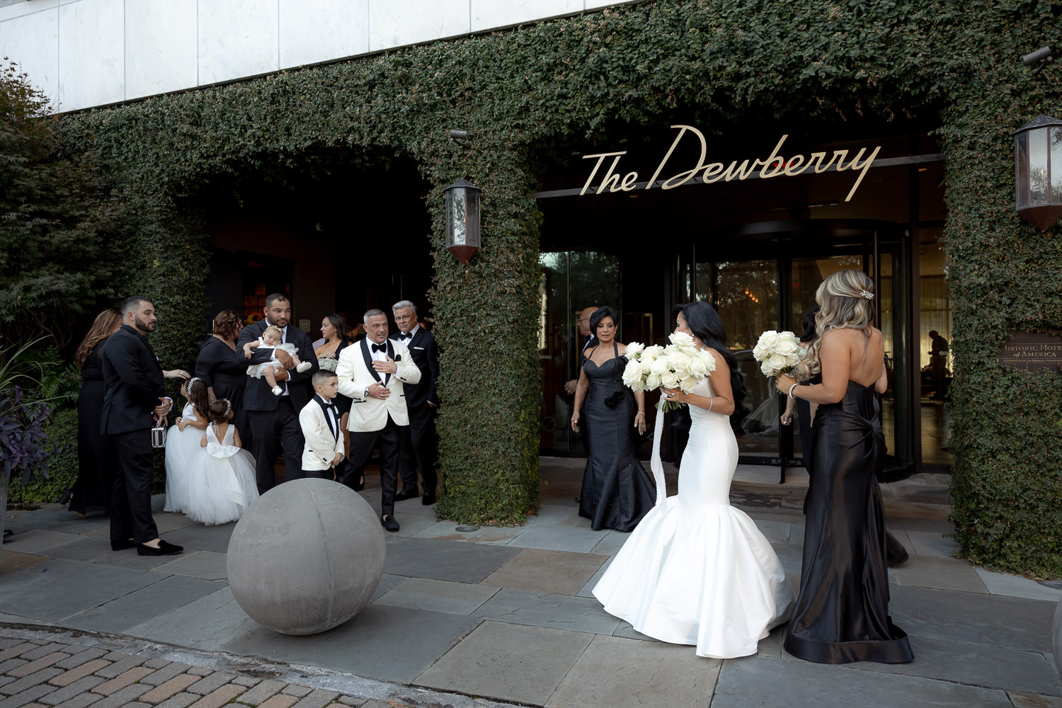 Wedding party gathering for portraits at Dewberry wedding. The dewberry sign on ivy overgrown wall