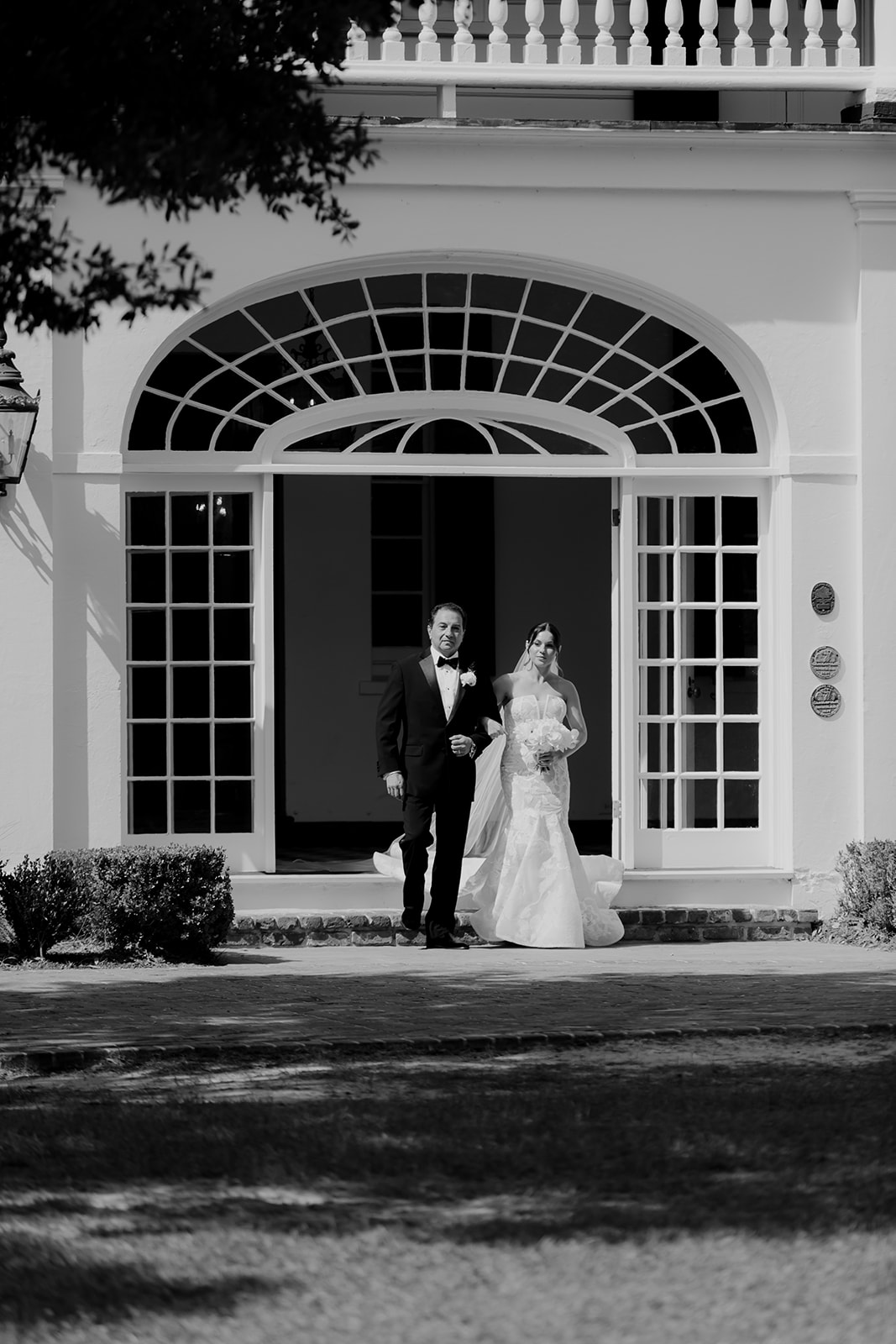 Bride is walking outside from Lowndes Grove towards ceremony space accompanied by her father