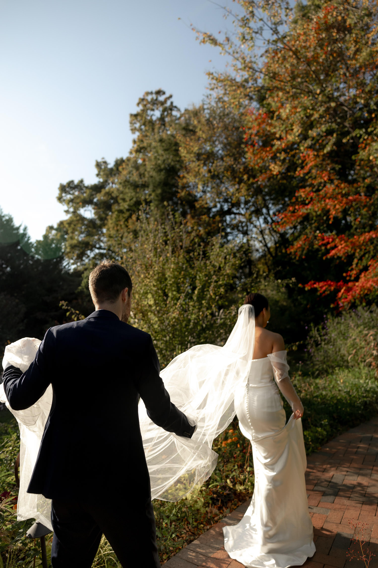 The groom carefully carrying the bride's dress and vail during couple portraits