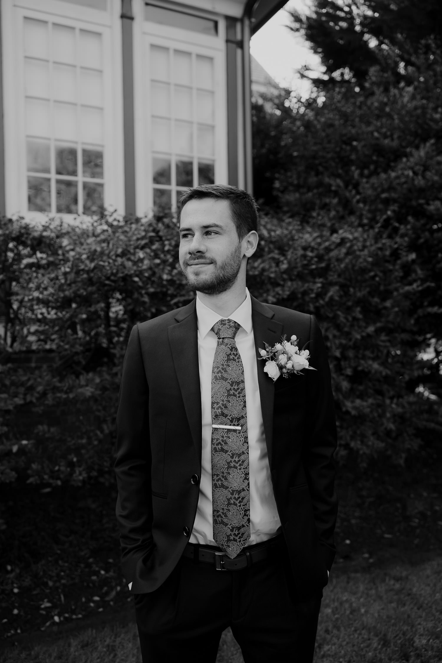 The groom in black and white with suit and tie clip