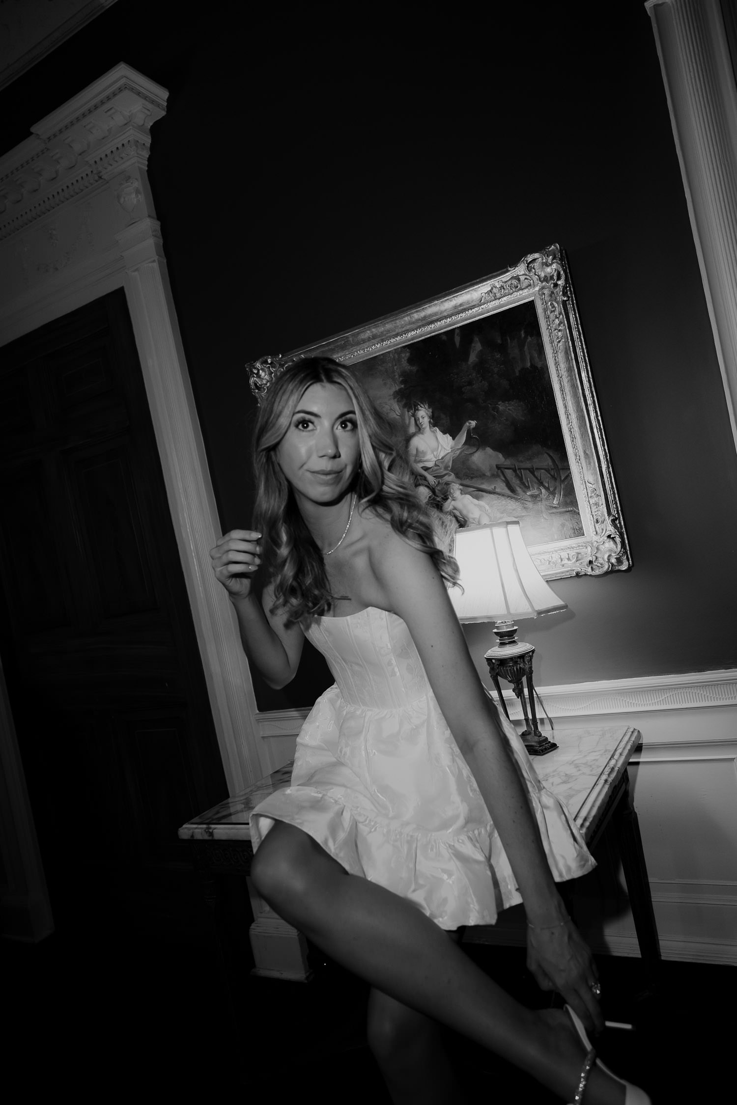 Charleston bride changed in shorter reception cocktail dress looking at camera with painting in background