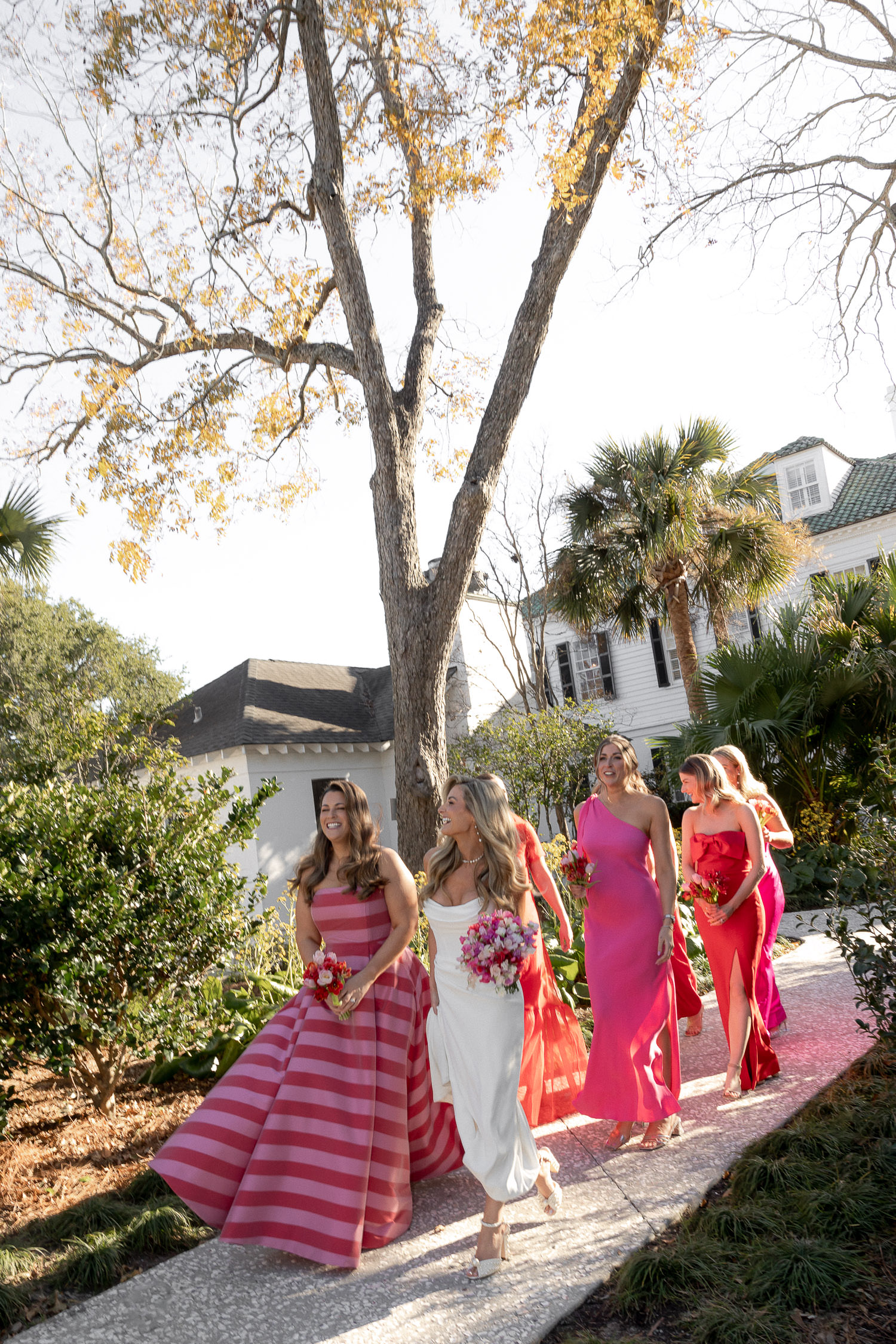 Bride and bridesmaids walking at lowndes grove shoing off the color palette for Hot pink & Red wedding