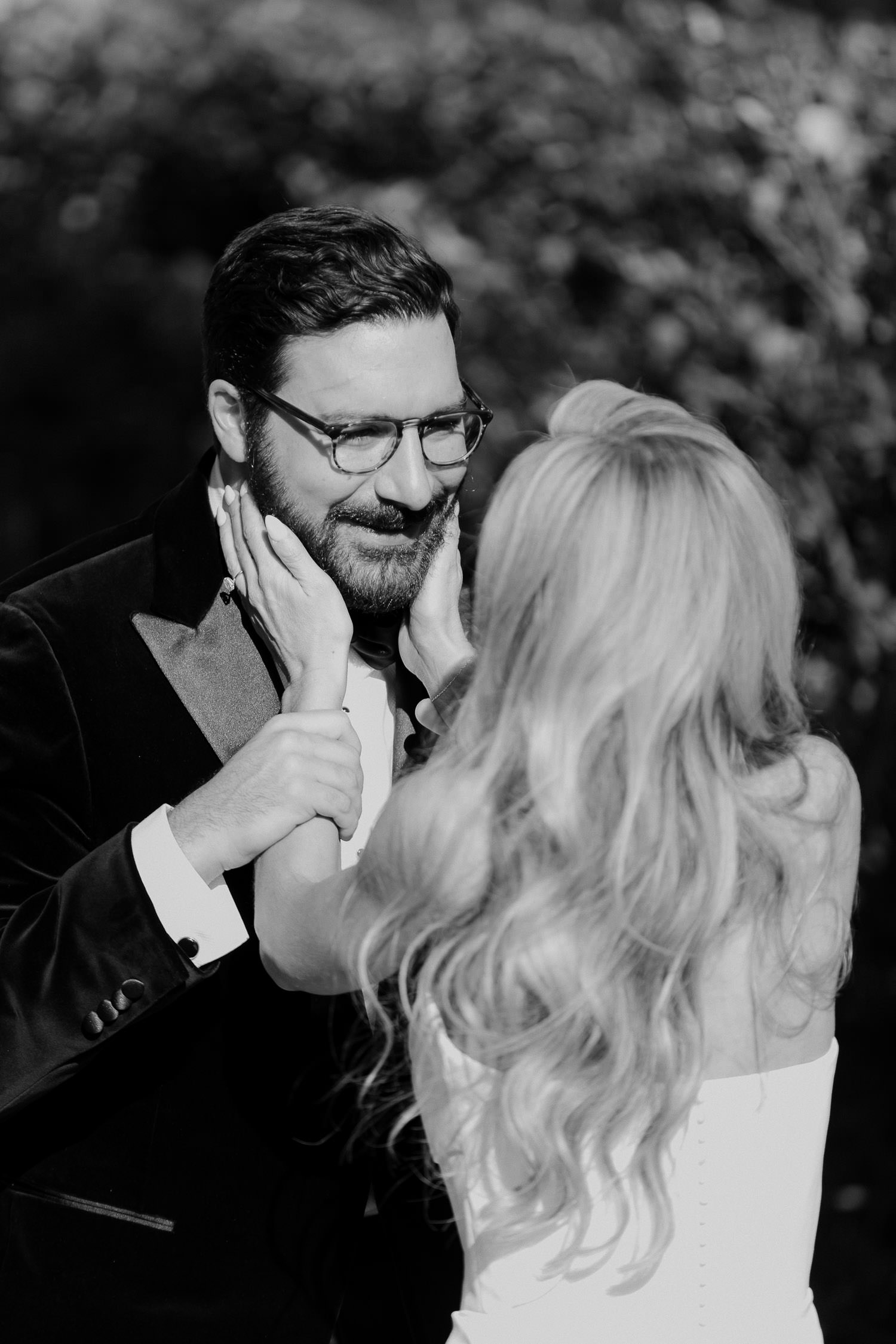 Pure emotions at the first look. Bride holding on to grooms face while he smiles at her. Hot pink & Red wedding at lowndes grove