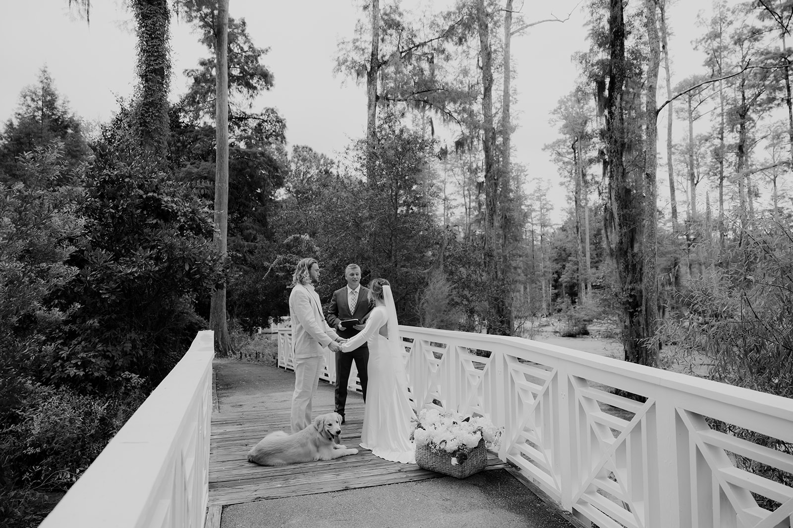 black and white photo of Cypress Gardens Elopement. Couple holding hands with officiant standing on bride. 