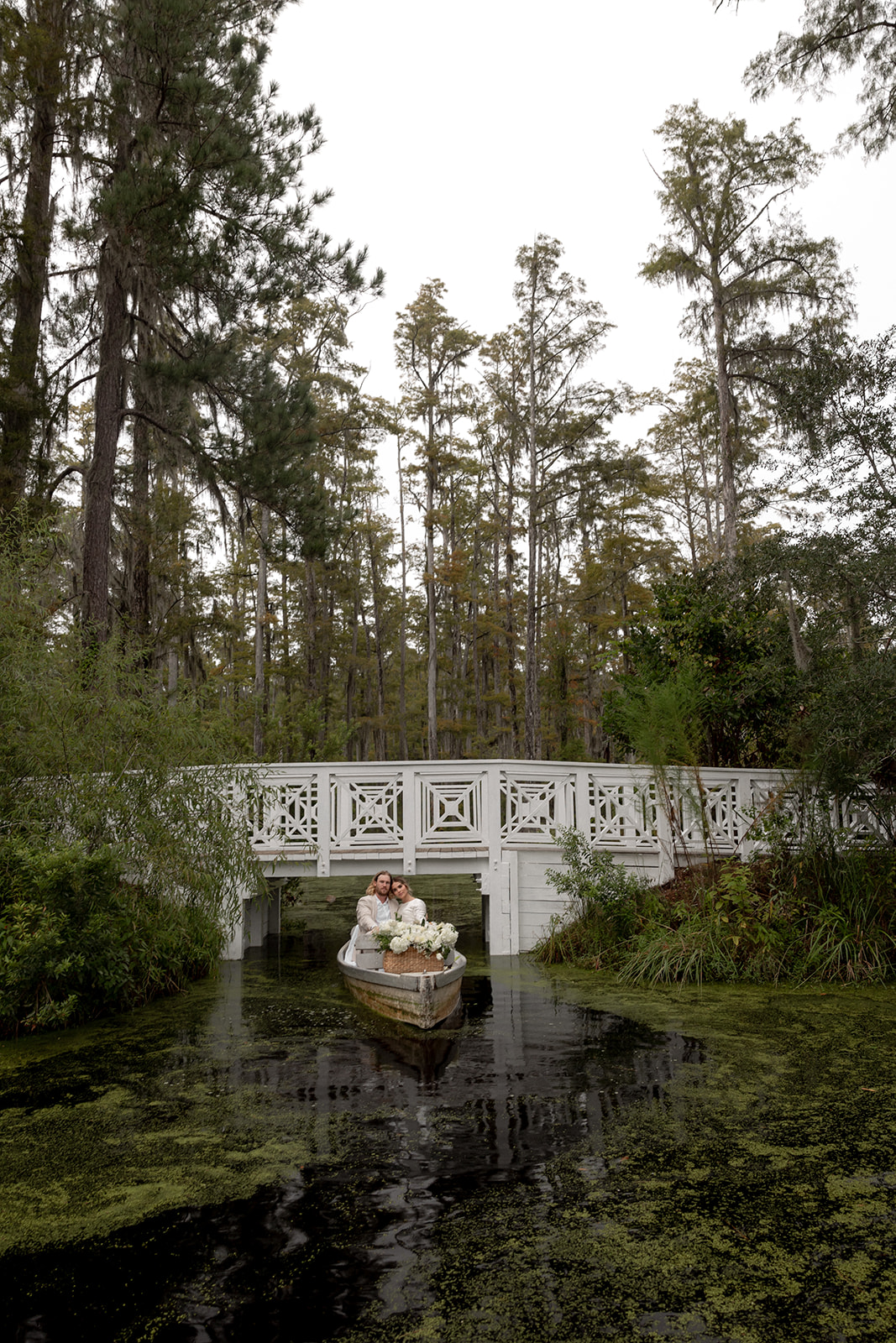 Couple in boat in font of white bride at Cypress Gardens