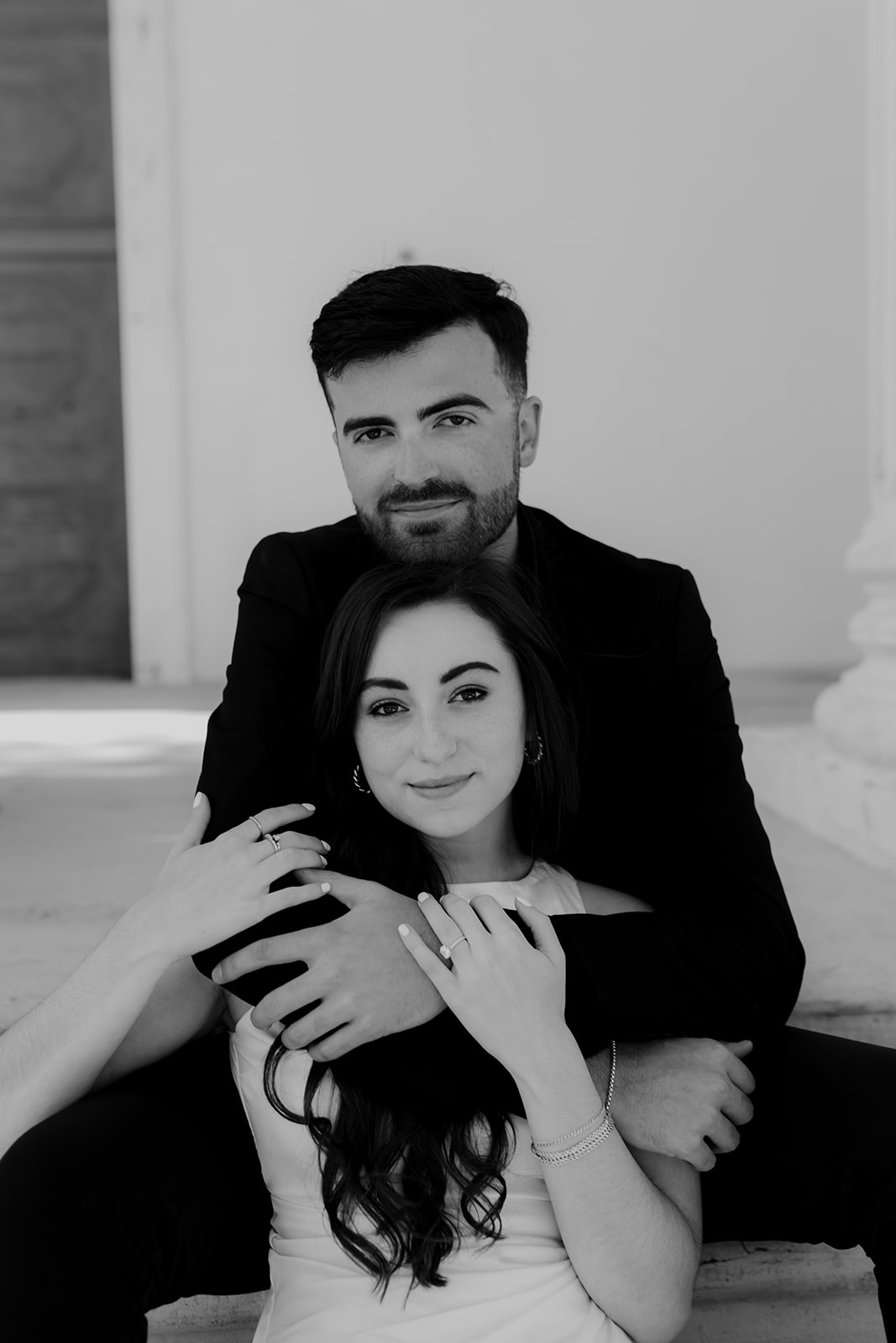 black and white protrait of couple. Sitting on stairs. Both looking into cmer