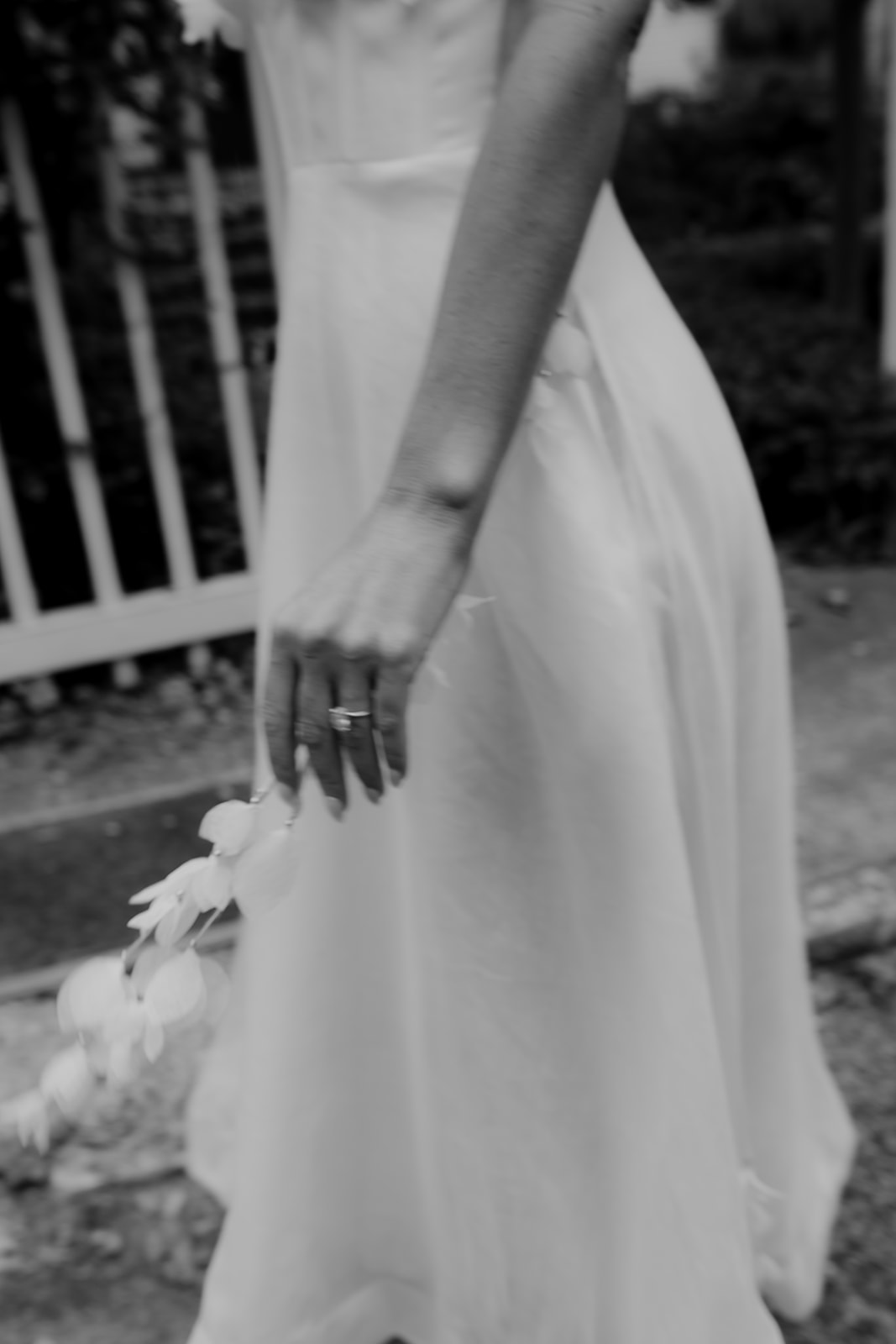 Black and white photo of engagement ring with white dress in background