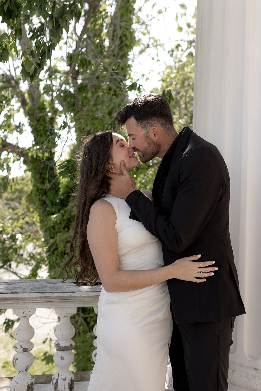 couple in black and white engagement attire kissing. He holds her cheek ahd she holds on to him