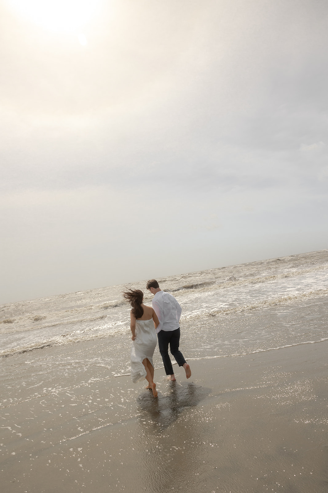 Couple running towards the water at Isle of Palms. 