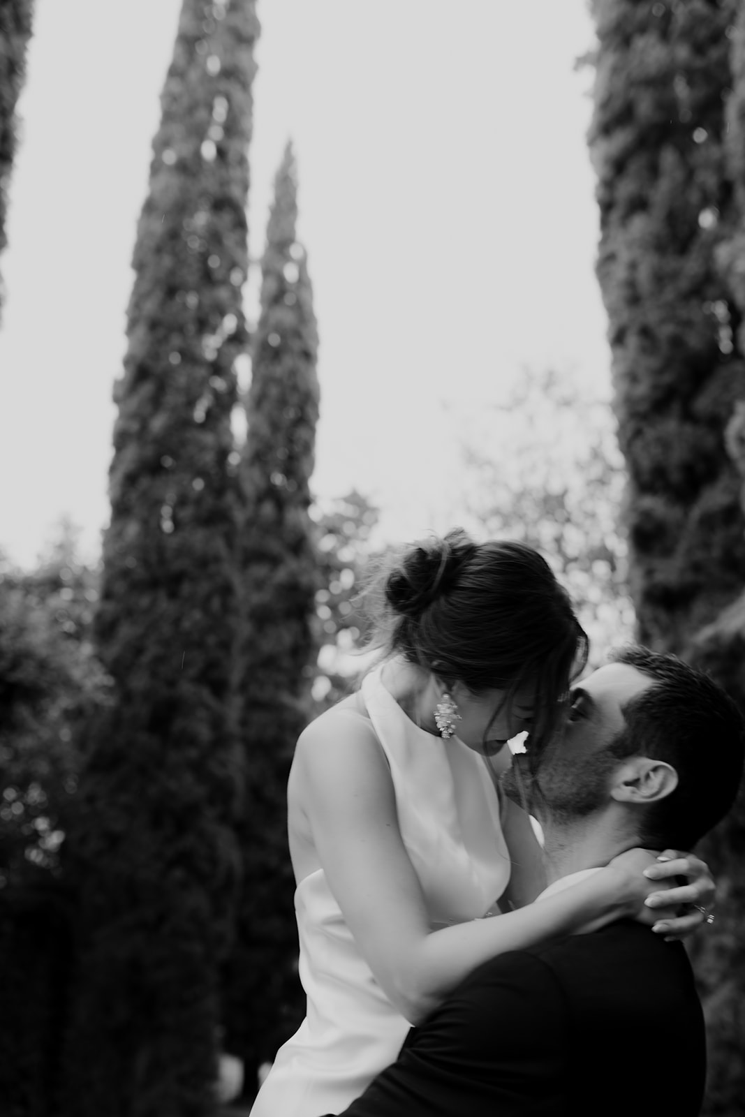 A kiss in blak and white with italian cypress in background