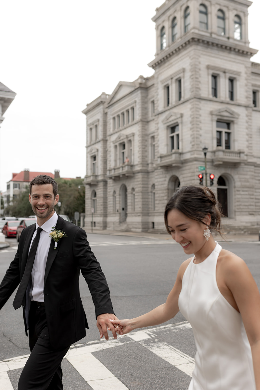 Man and woman holding hand while walking at intersection in Charleston. Candid engagement photo with beautiful Engagement Look