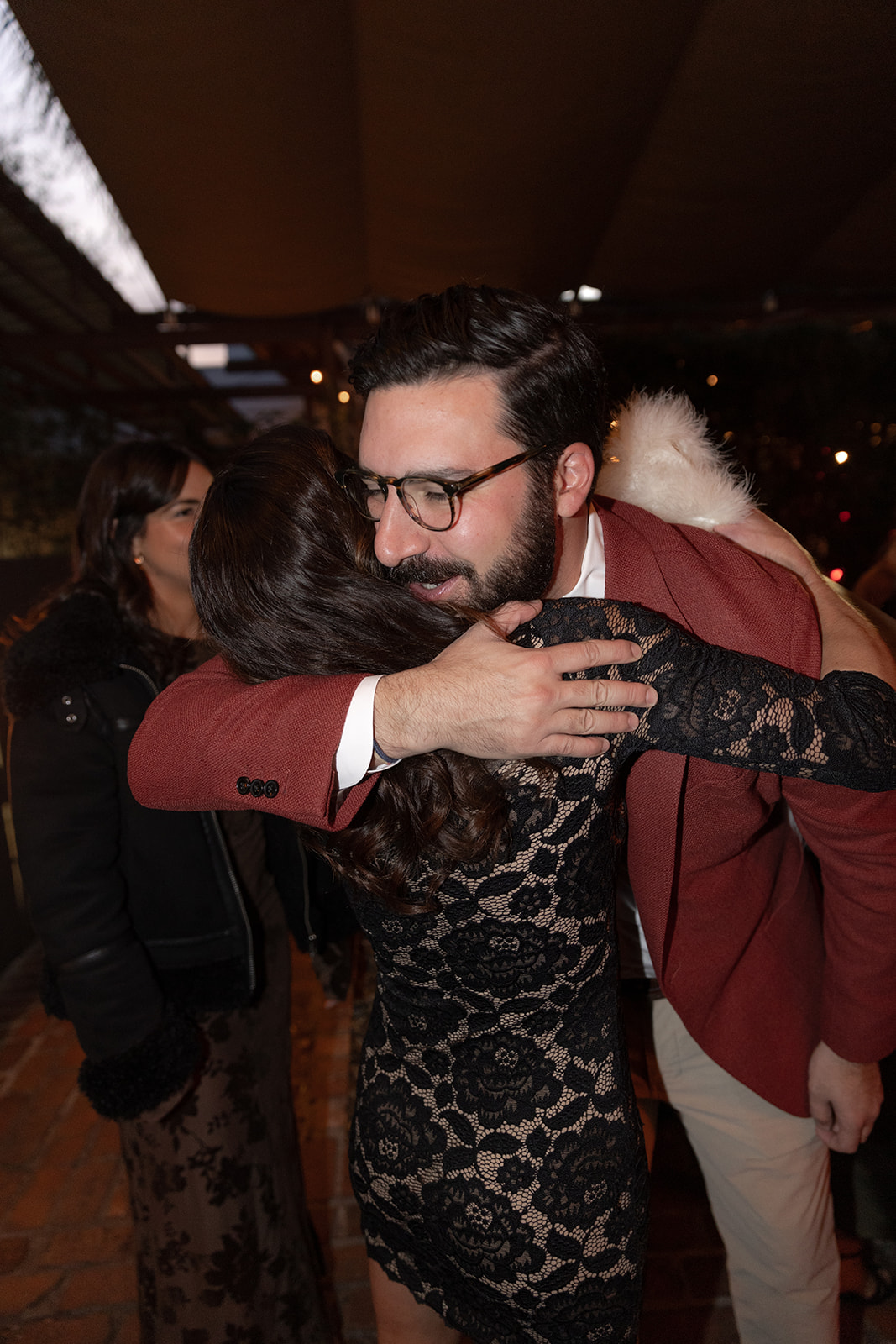 Groom greeting guest to rehearsal dinner with a hug