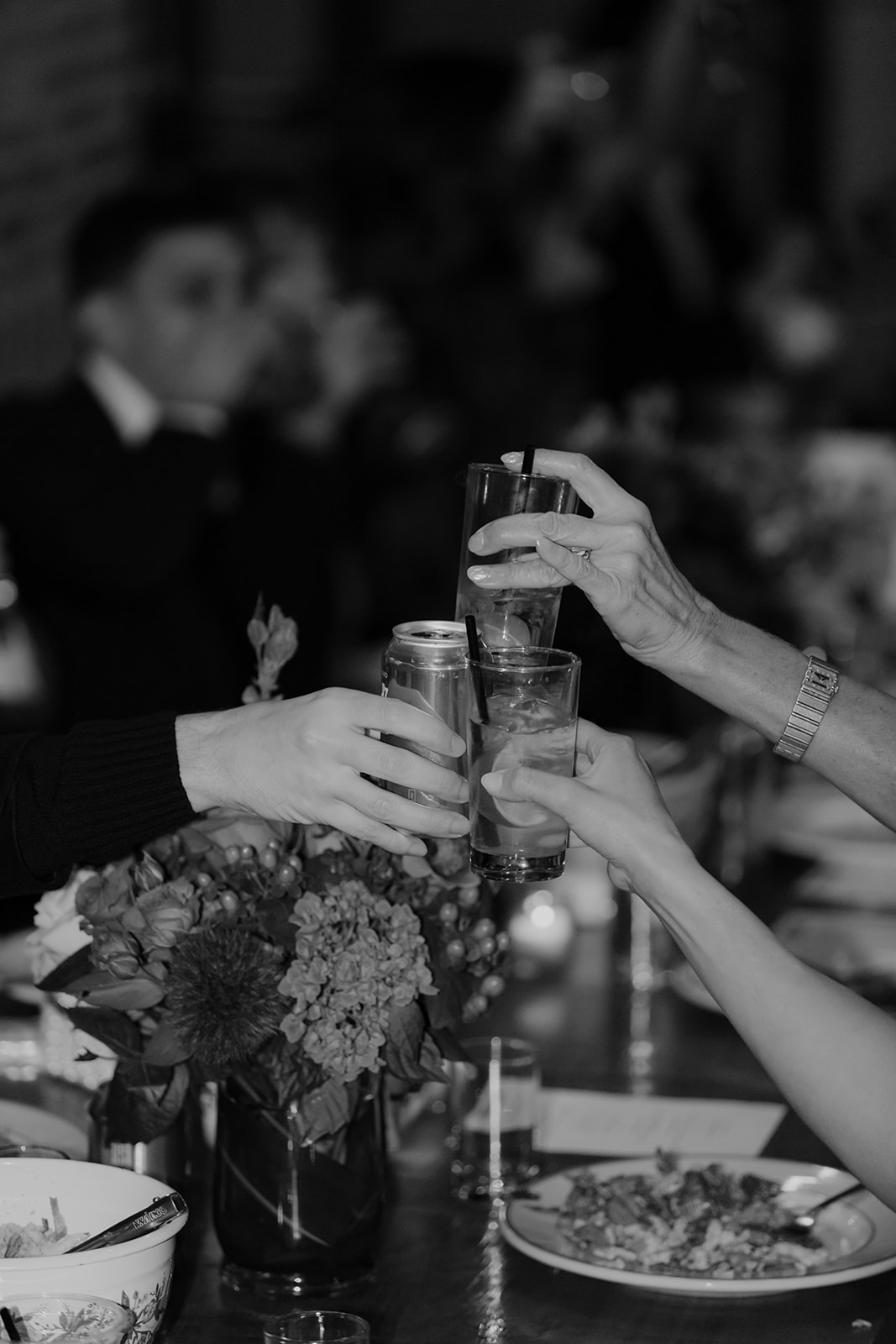 Close-up photo of rehearsal dinner guests clink glasses with each other