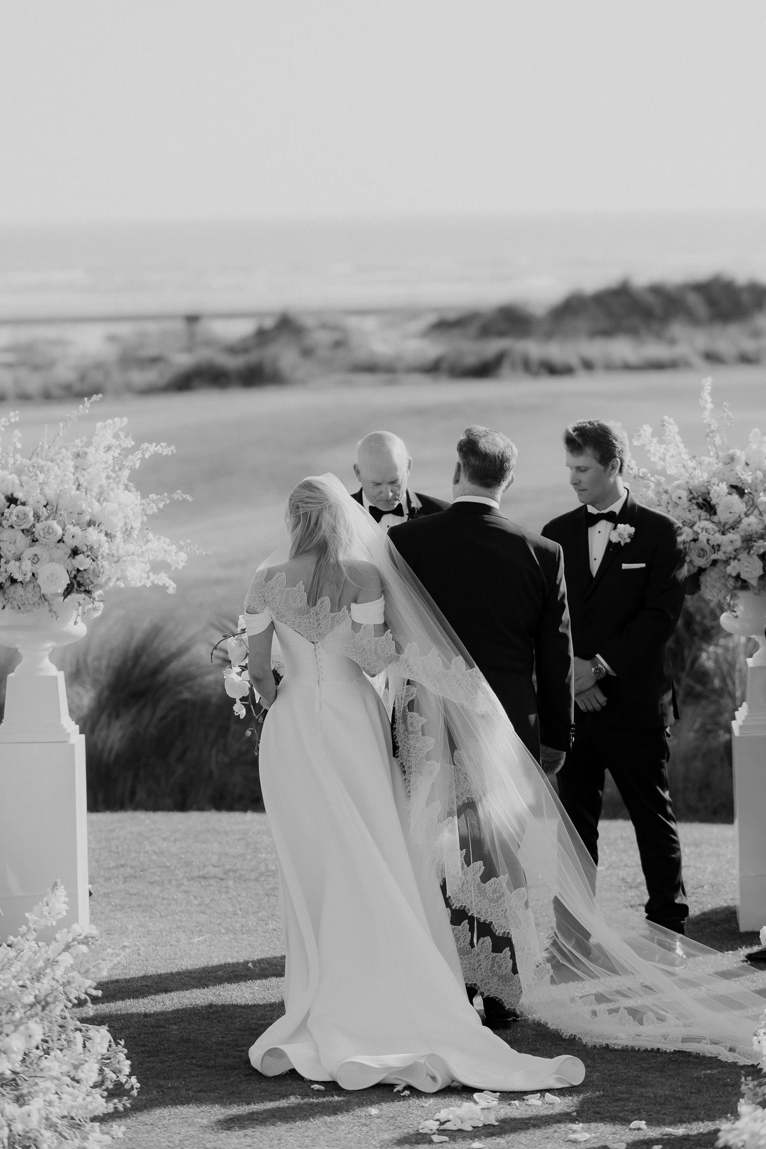 Father of the bride gives daughter away at ocean course ceremony.