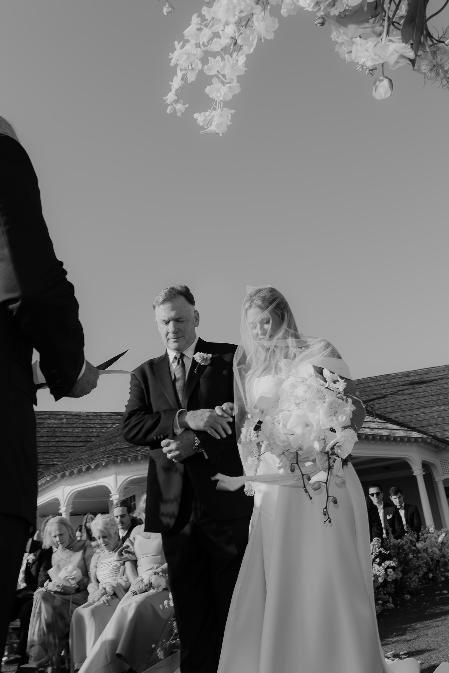 Father of the bride leading his daughter down the aisle photographed in black and white