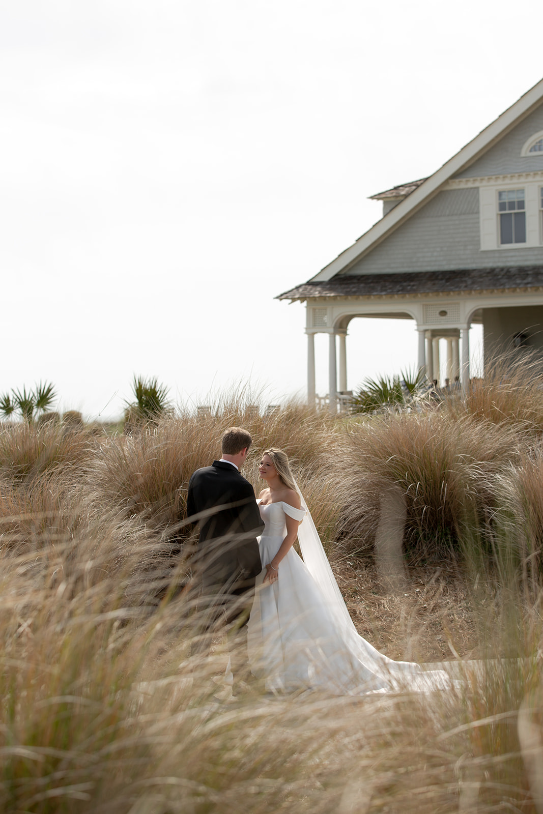 Bride and groom look at each other surrounded by pink muhly grass that grows in the lowcountry